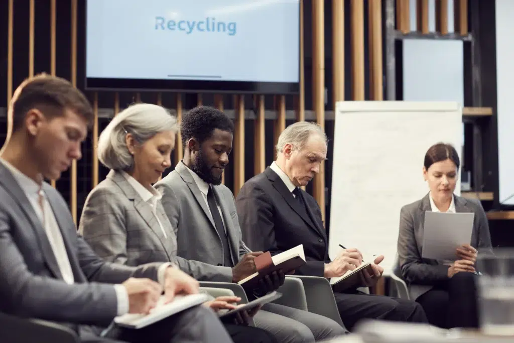 Diverse corporate executives taking notes during a seminar on why is responsible AI practices important to an organization for legal compliance.