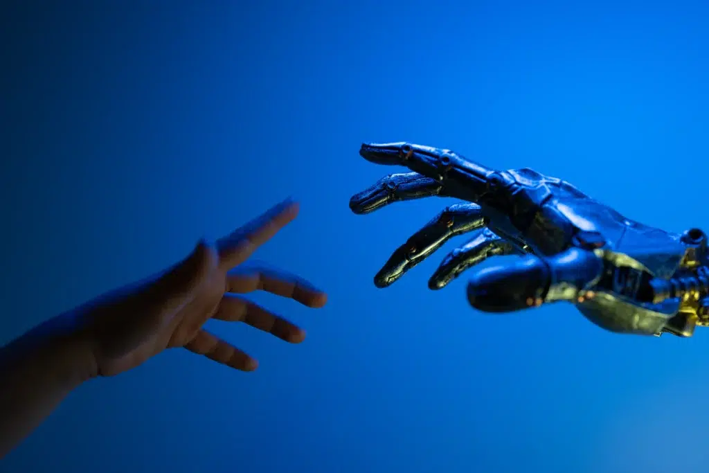 human hand reaching toward a robotic hand, illustrating the balance of data anonymization vs data masking in human-centric AI.