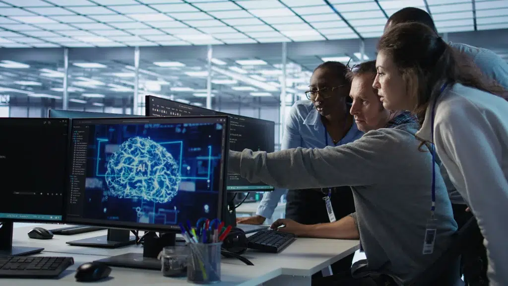 IT team collaborating on AI incident response while reviewing AI system alerts on monitors