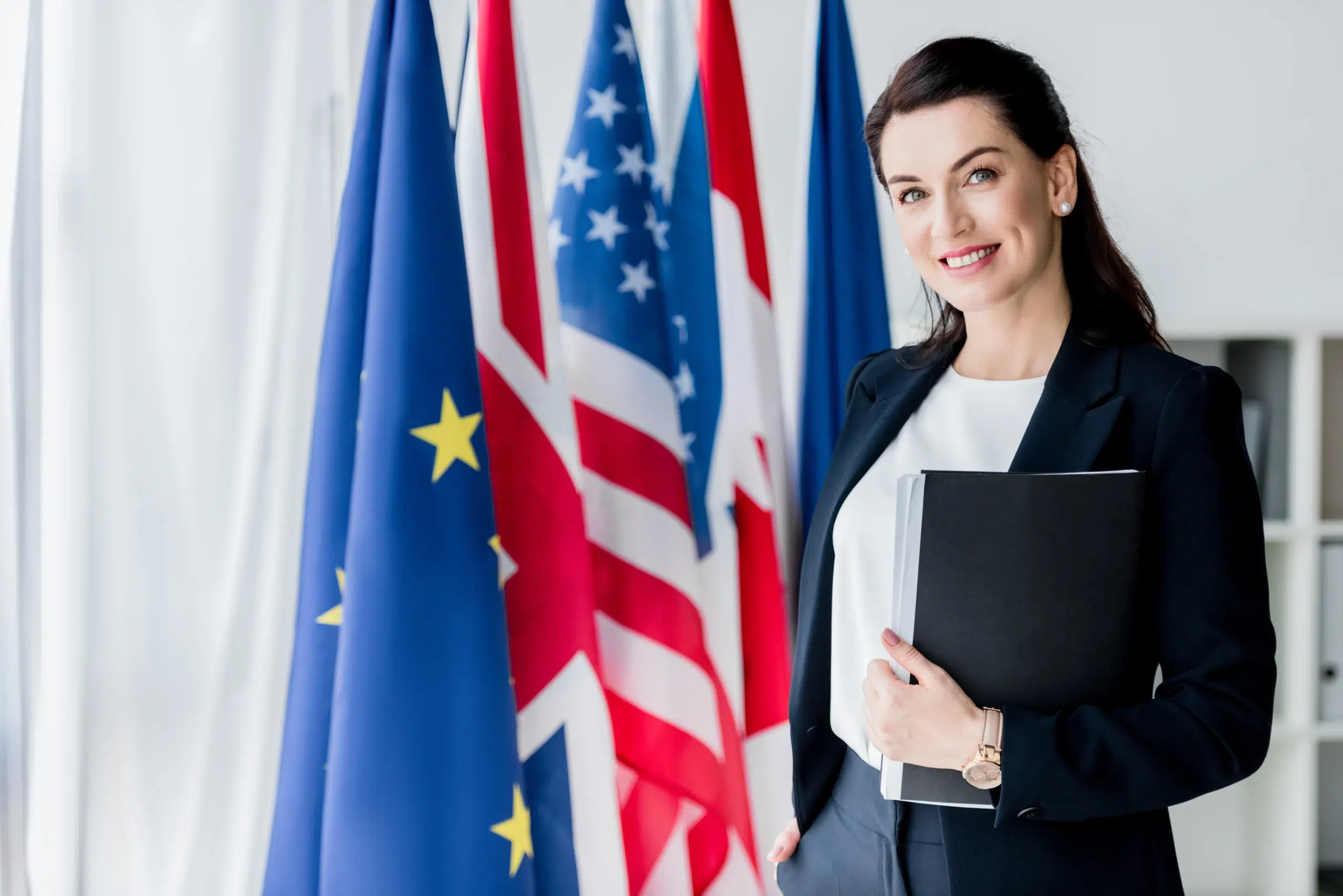 Businesswoman standing beside EU, US and UK flags reflecting EU AI Act news today in 2026 and its global reach